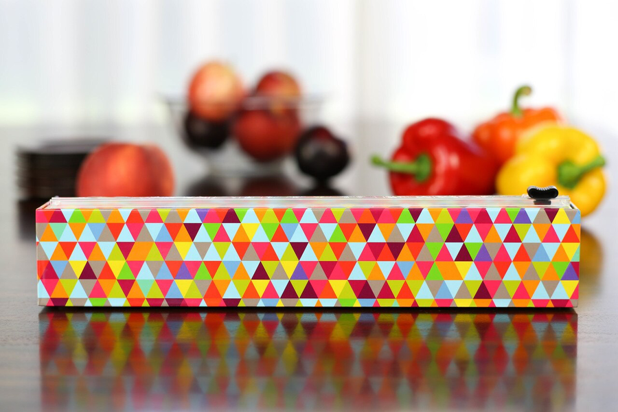 triangles plastic wrap dispenser displayed in a kitchen with fruits and veggies behind it