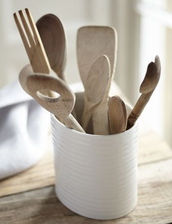 white crock filled with an assortment of wooden utensils on wood countertop.