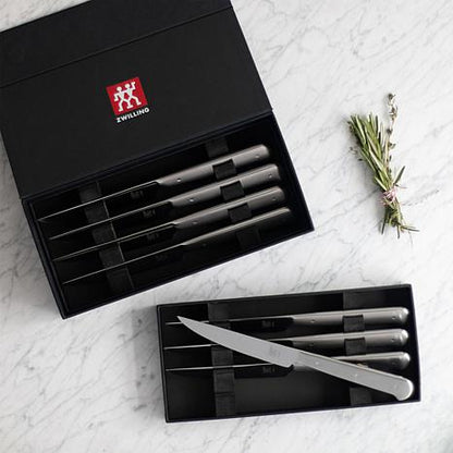 boxed steak knife set on grey marble countertop with a sprig of rosemary