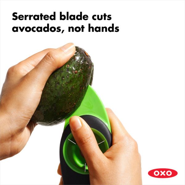 hands holding avocado and slicer slicing avocado.