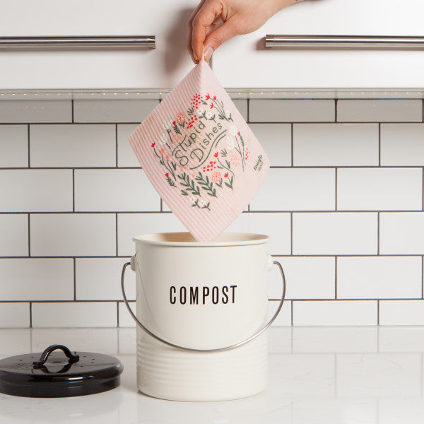 hand holding dish cloth above compost pail.