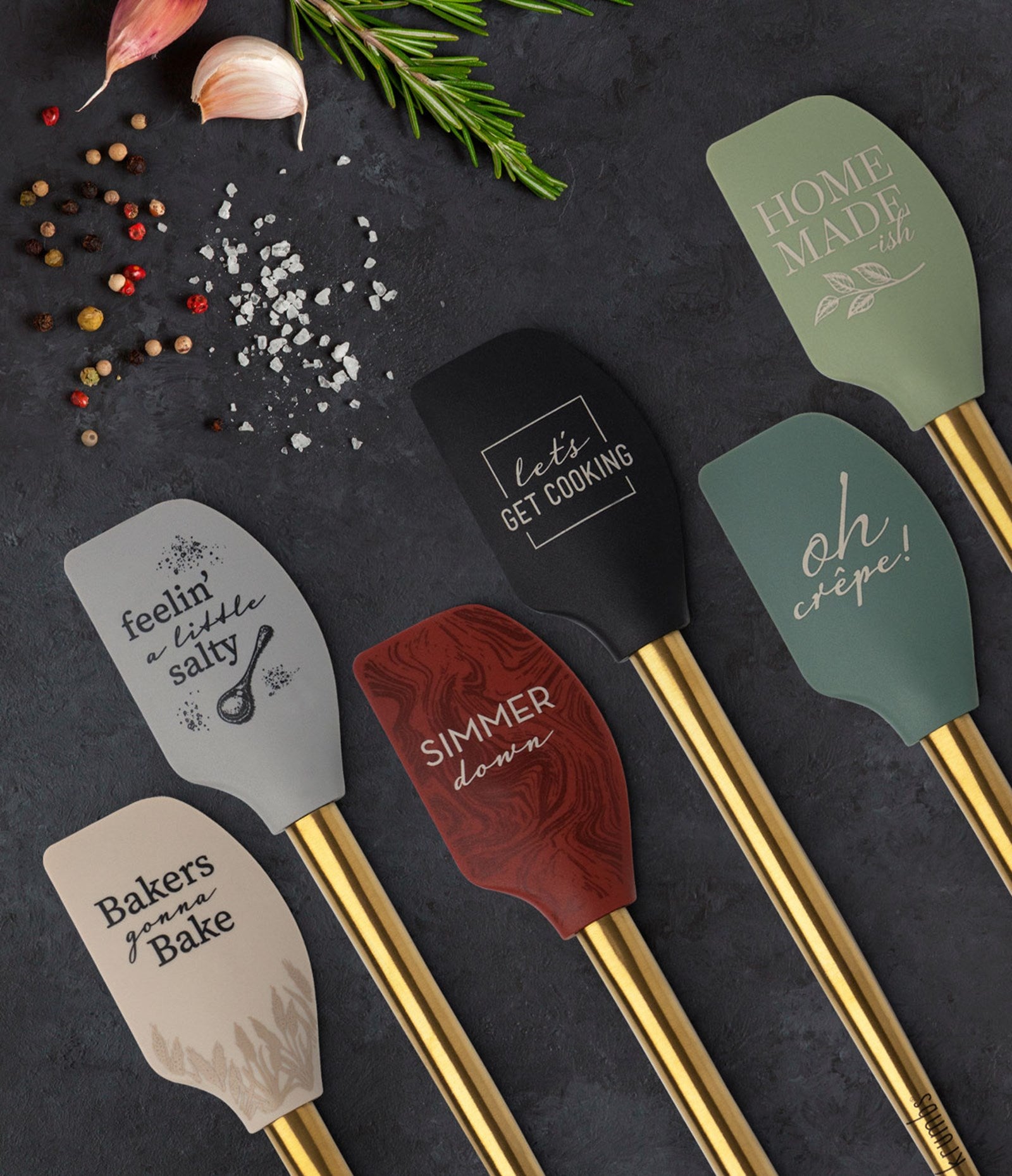 six elements spatula displayed on a gray table with spices