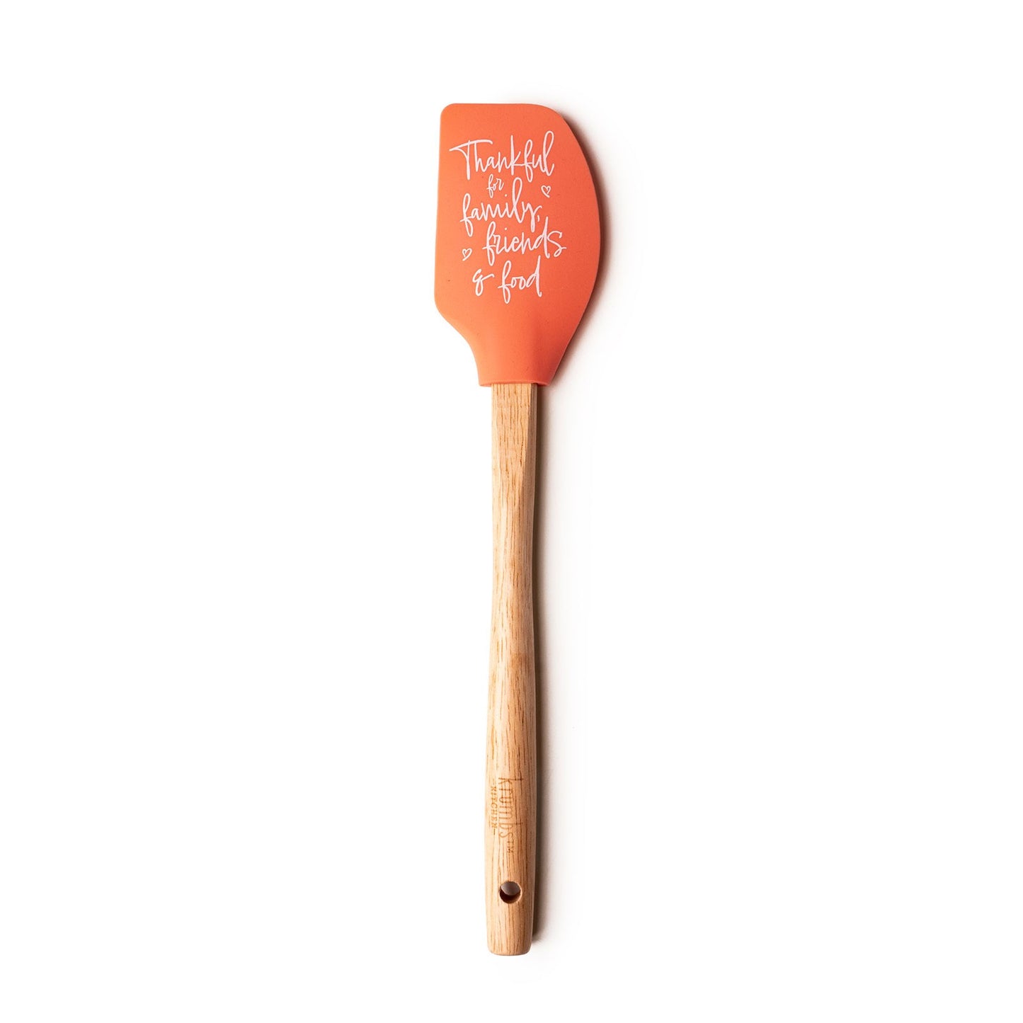 orange spatula with "thankful for family, friends, and food" printed on it and a wooden handle.