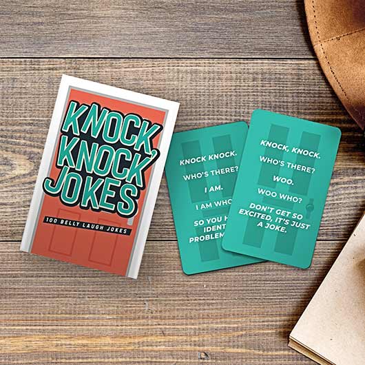 knock knock jokes displayed next to two cards on a dark stained wood table 