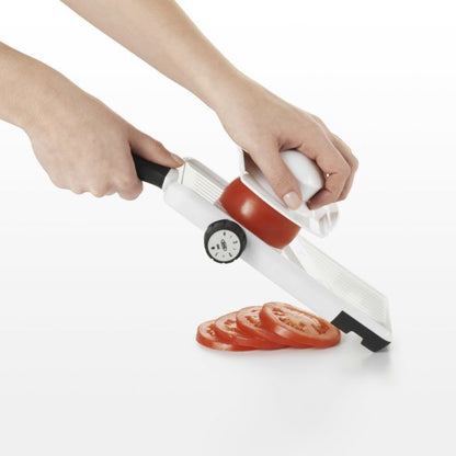 hands holding slicer and slicing tomato.