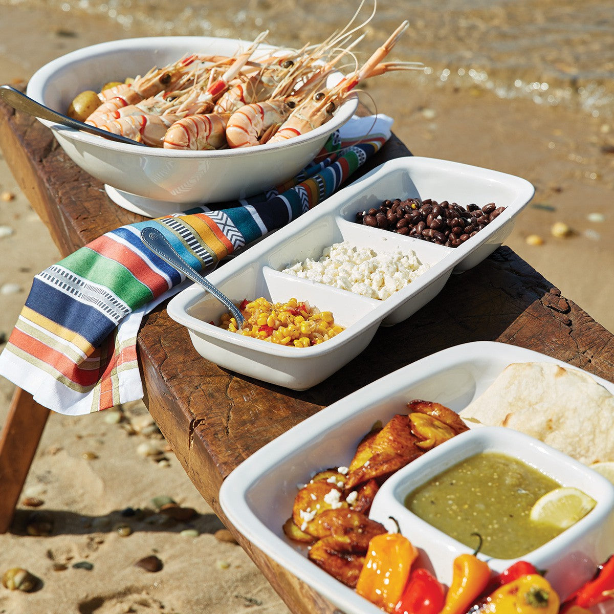 display of puro serveware on a wood bench at a beach