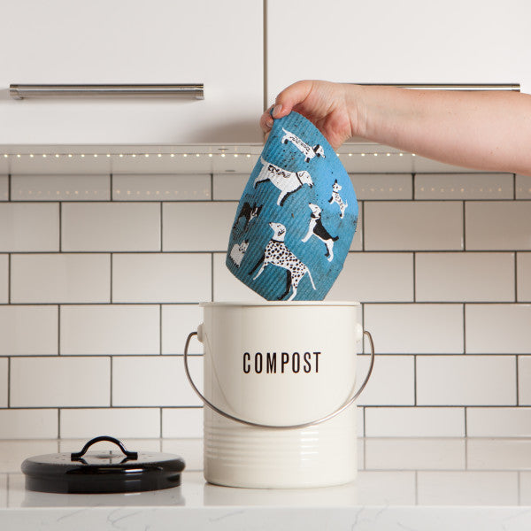hand holding swedish dish cloth above compost pail.