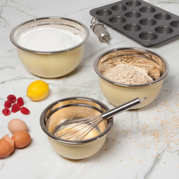mixing bowls filled with batter, flour, and oats on countertop with eggs, whisk, and muffin pan.
