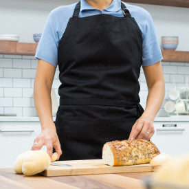 person wearing apron in kitchen.