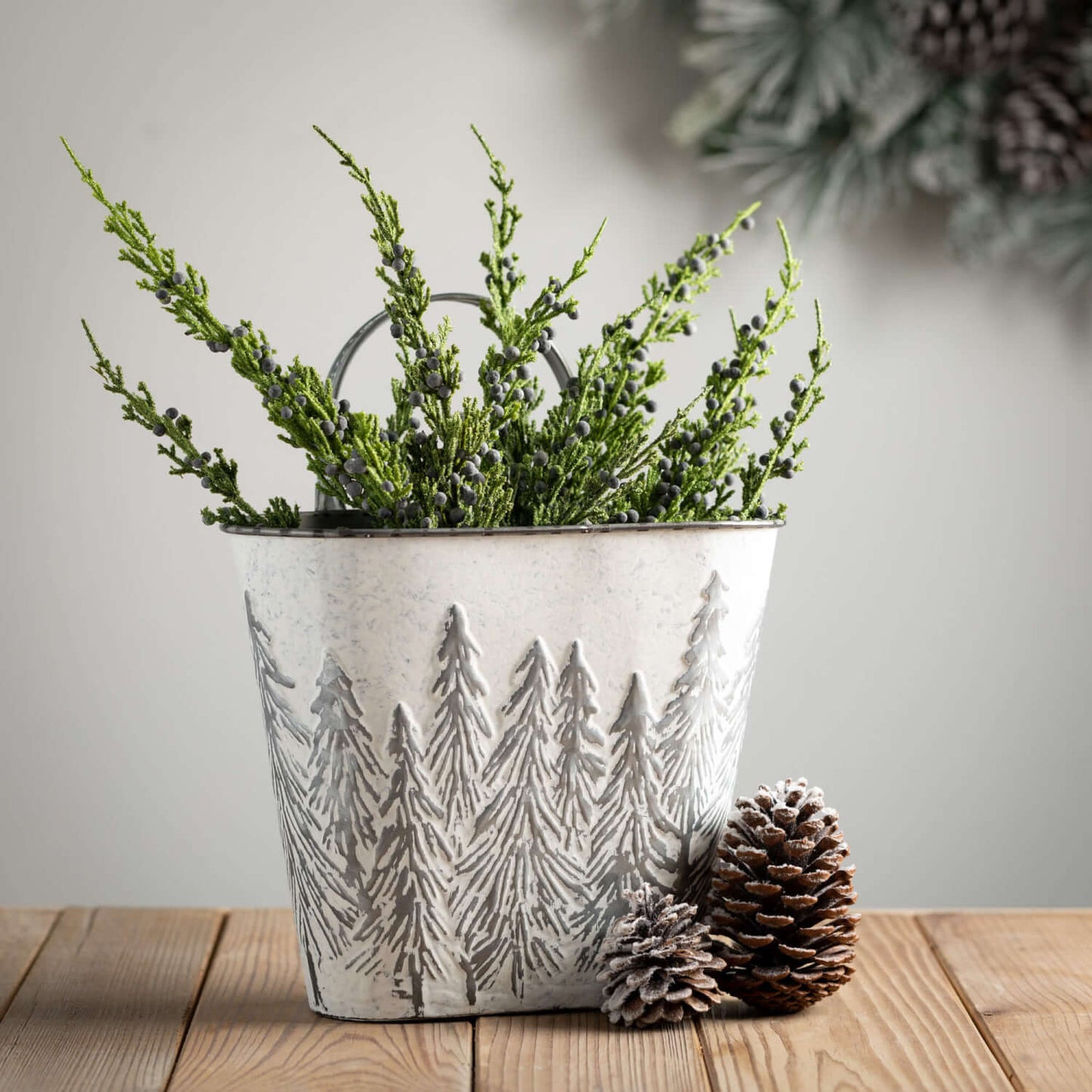 bucket on table with greenery in it.