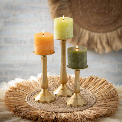 all three sizes of the gilded classic pillar holders displayed with lit candles on a grass placemat