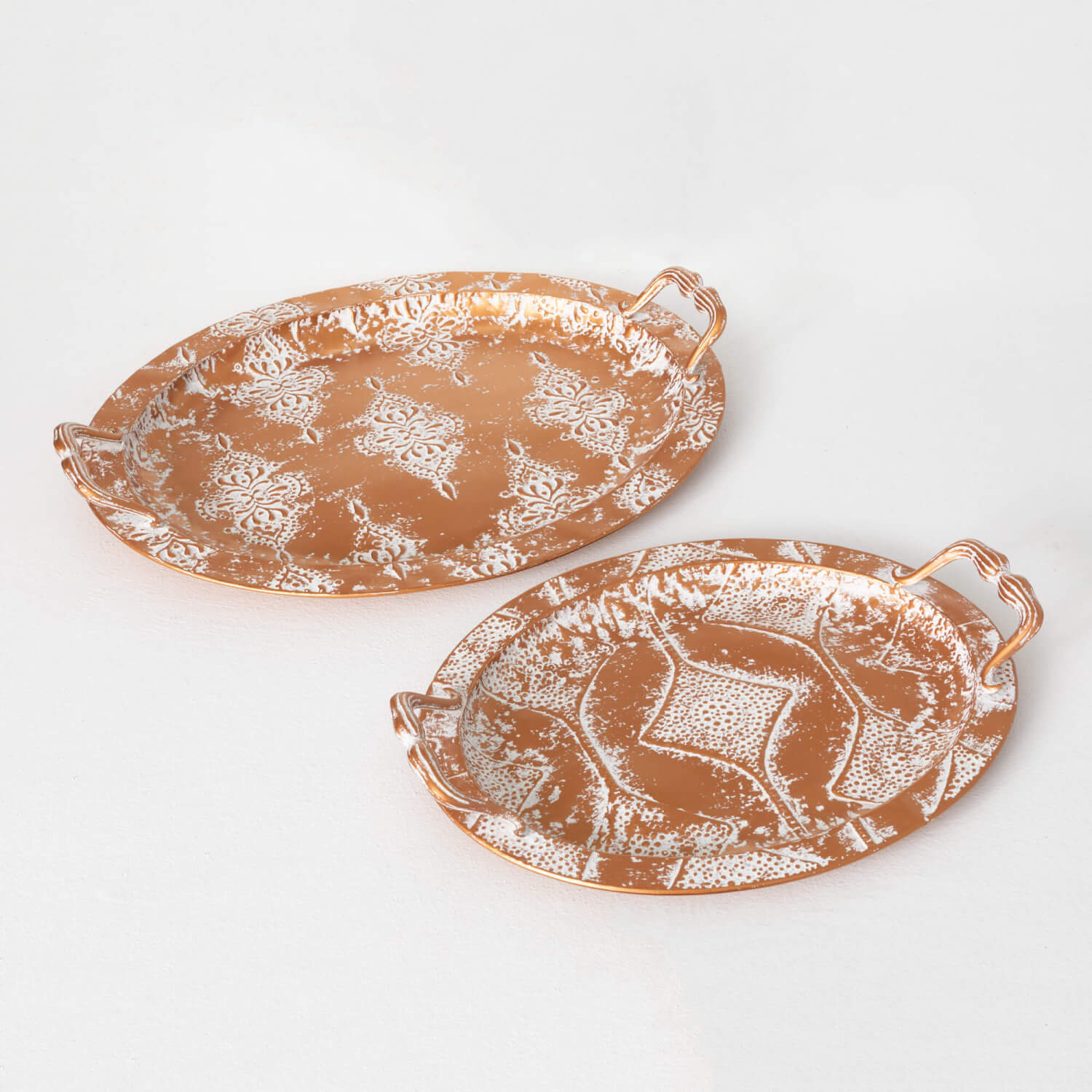 2 golden trays with handles and white washed geometric designs.