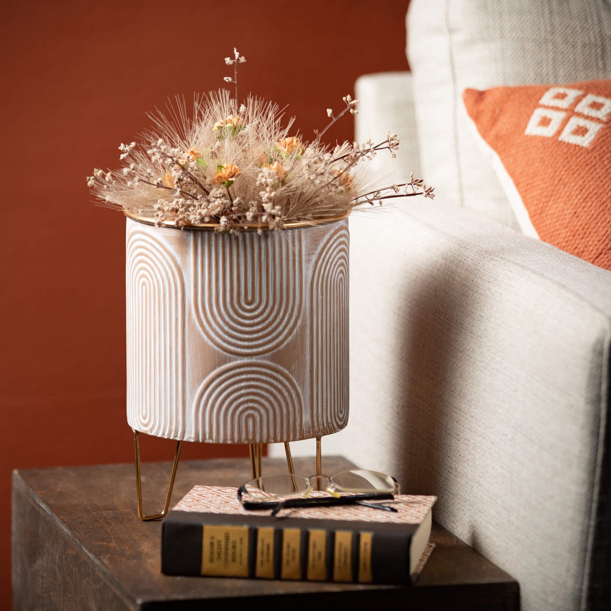 planter filled with grasses and berries set on a side table next to a couch.