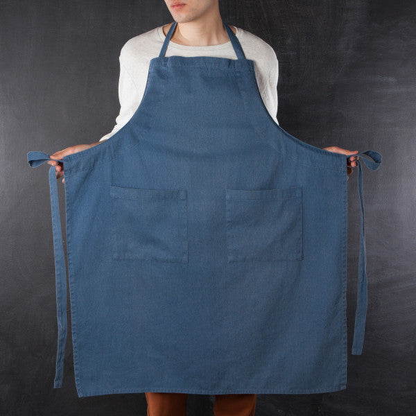 person wearing apron and holding the ties out to the side.