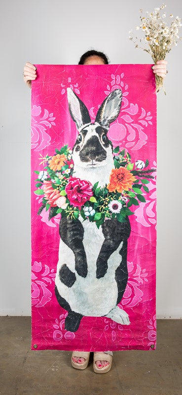 bright pink paper with black and white bunny wearing a necklace of bright flowers.