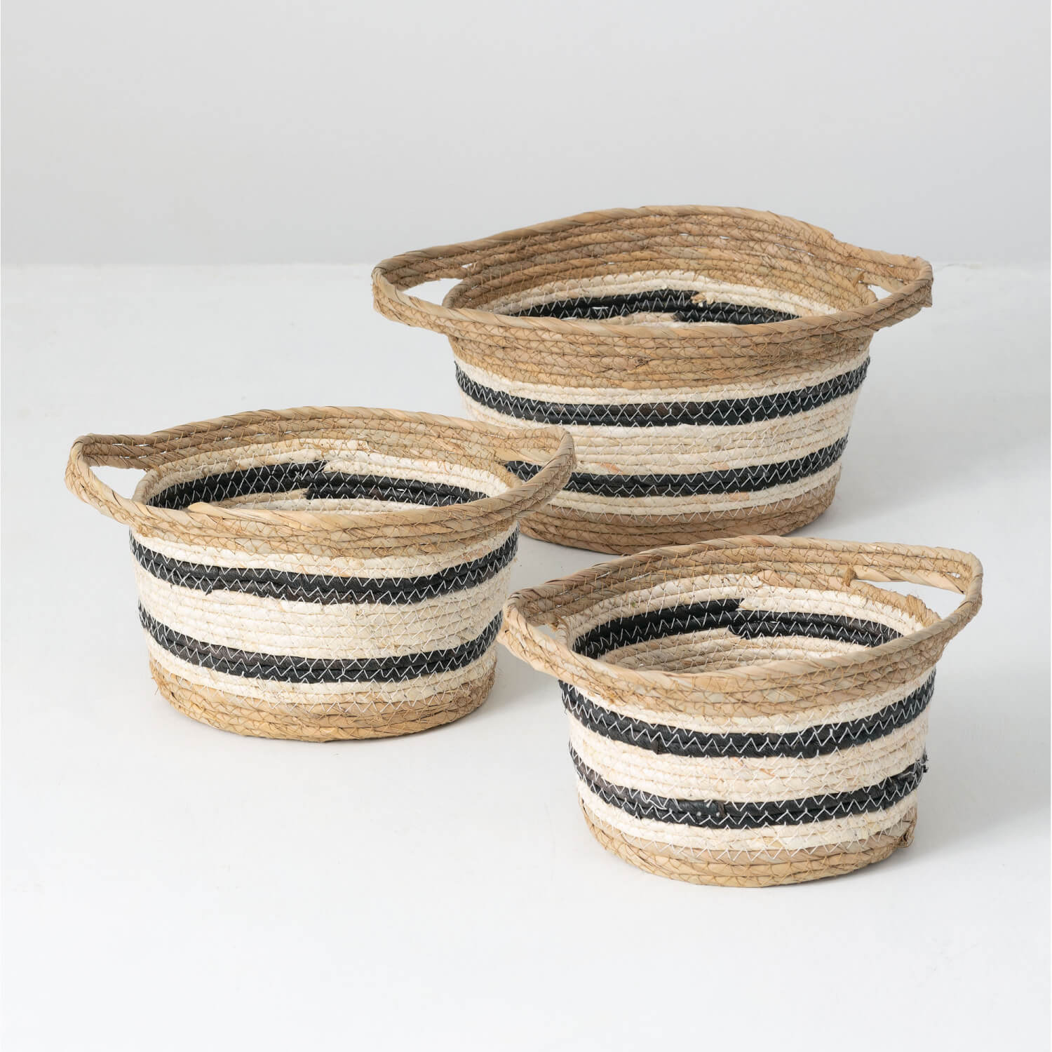 small, medium, and large baskets on white background. baskets are made from natural colored seagrass and white and blue rope woven and stitched together.