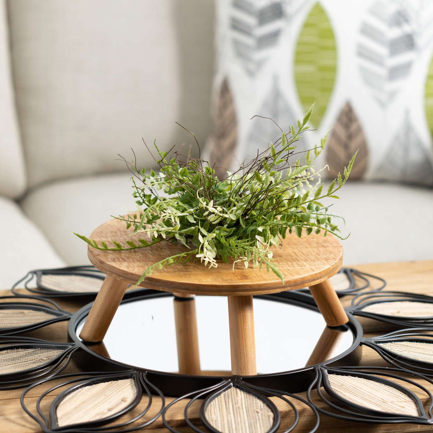 riser arranged with greenery on mirror on coffee table, couch and pillow in background.