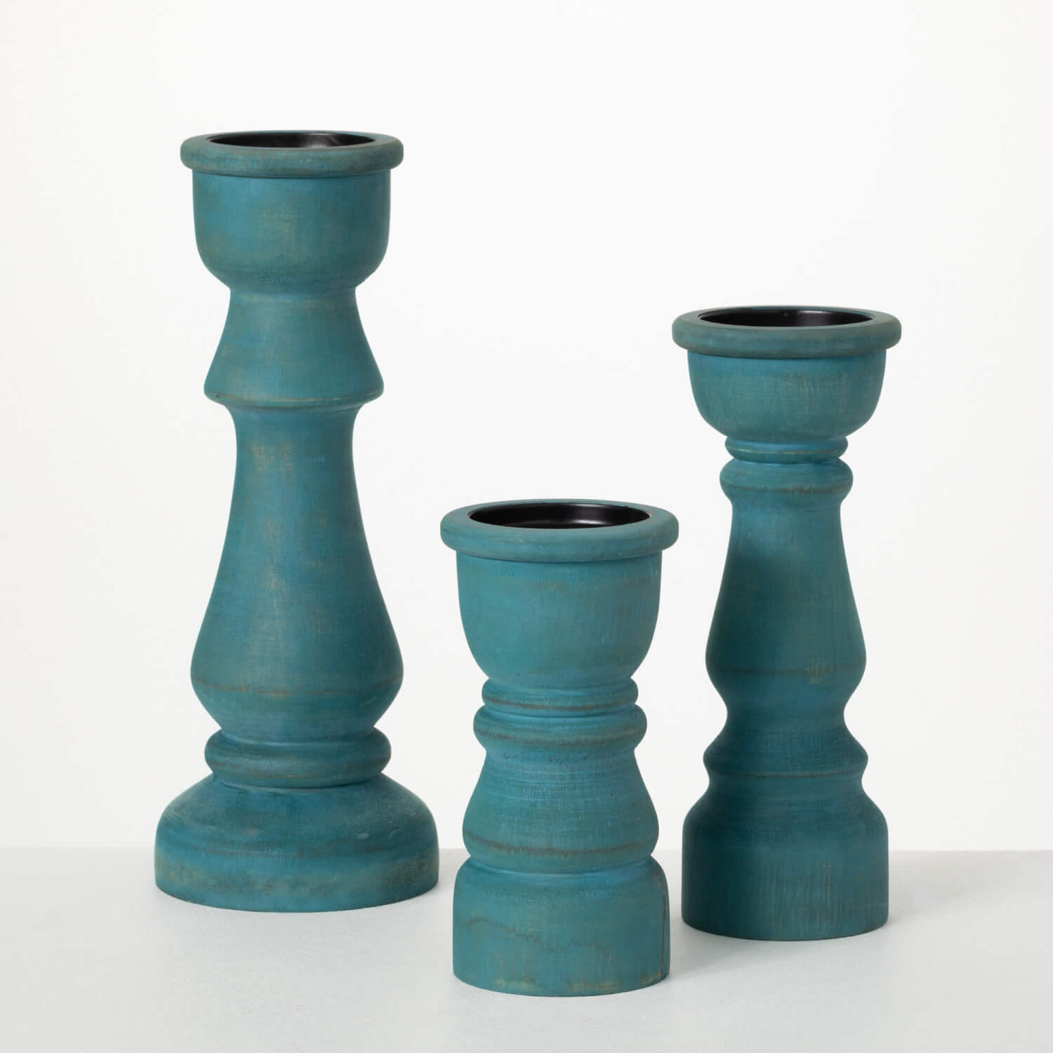 3 sizes of distressed turquoise candle sticks with spindle-style silhouettes and a light grey wash finish.