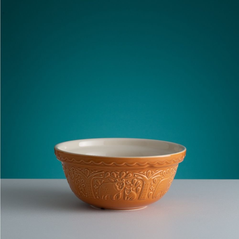 dark yellow bowl with bear in the forest pattern on a countertop with a teal background.