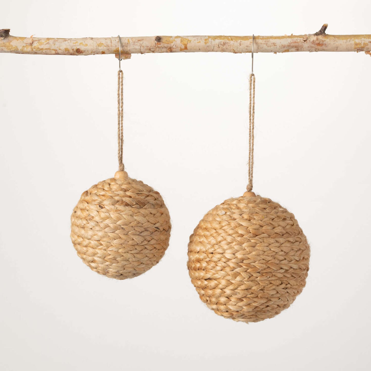 2 woven jute ball ornaments hanging from a branch.