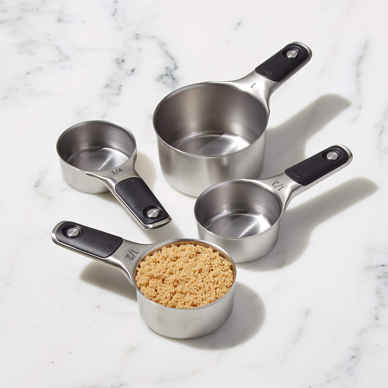 measuring cups on marble counter, one filled with brown sugar, the others empty.