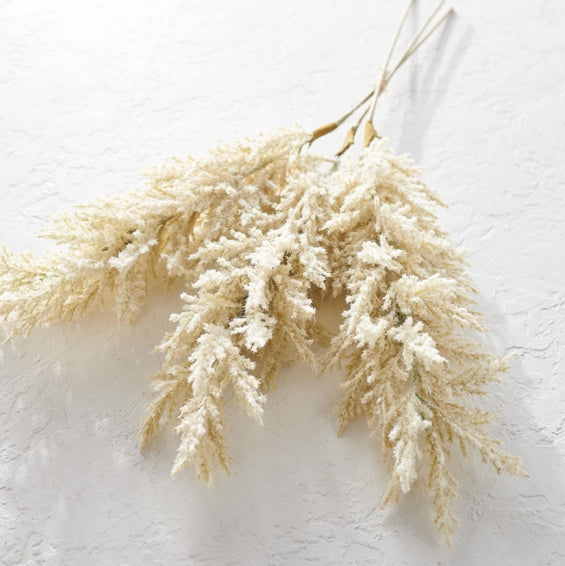 artificial pampas grass stems laying on a white table.