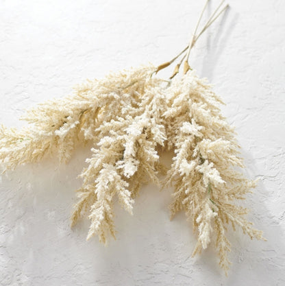 artificial pampas grass stems laying on a white table.