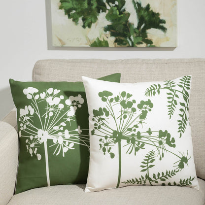 both green with white flowers and white with green flowers pillow displayed on a tan sofa beneath a green and cream painting
