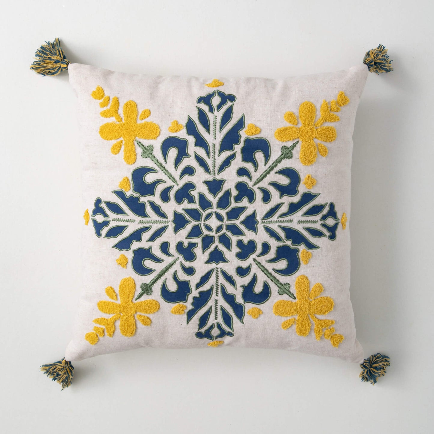 off-white pillow with blue and yellow floral mandala design.