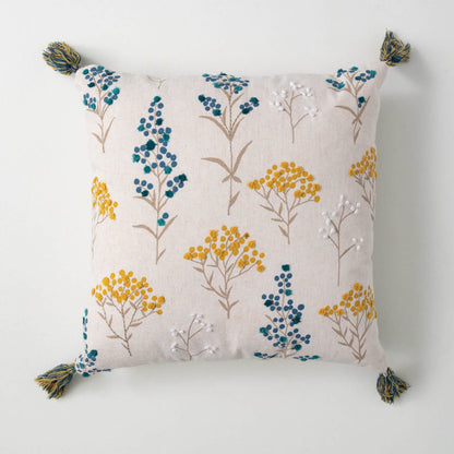 off-white pillow covered in dotted blue and yellow florals with french knot details and simple grey stems.