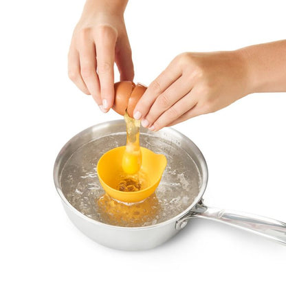 hands cracking egg into poacher in pot of boiling water.