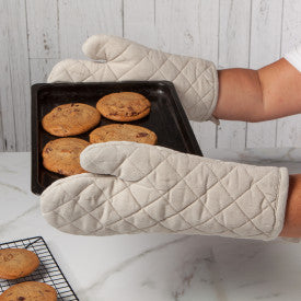 hands wearing oven mitts holding a pan of cookies.