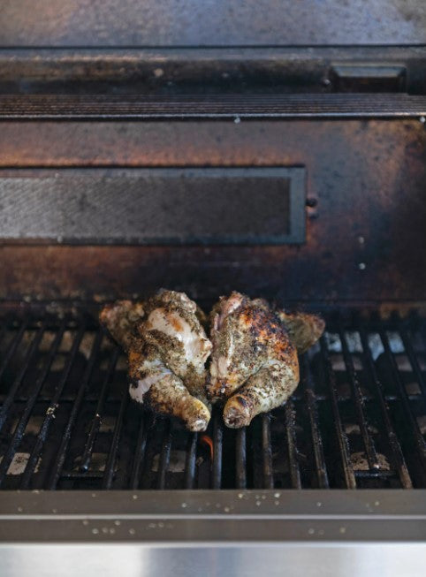 a seasoned and cooked chicken displayed on a hot grill
