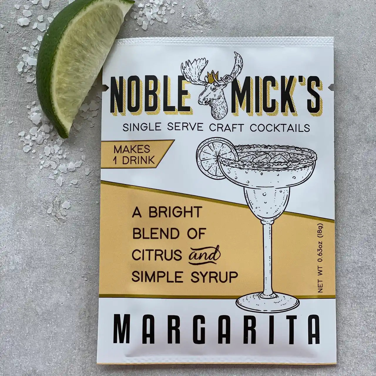 noble mick's single serve packet of Margarita mix on a bar top with salt and a lime.