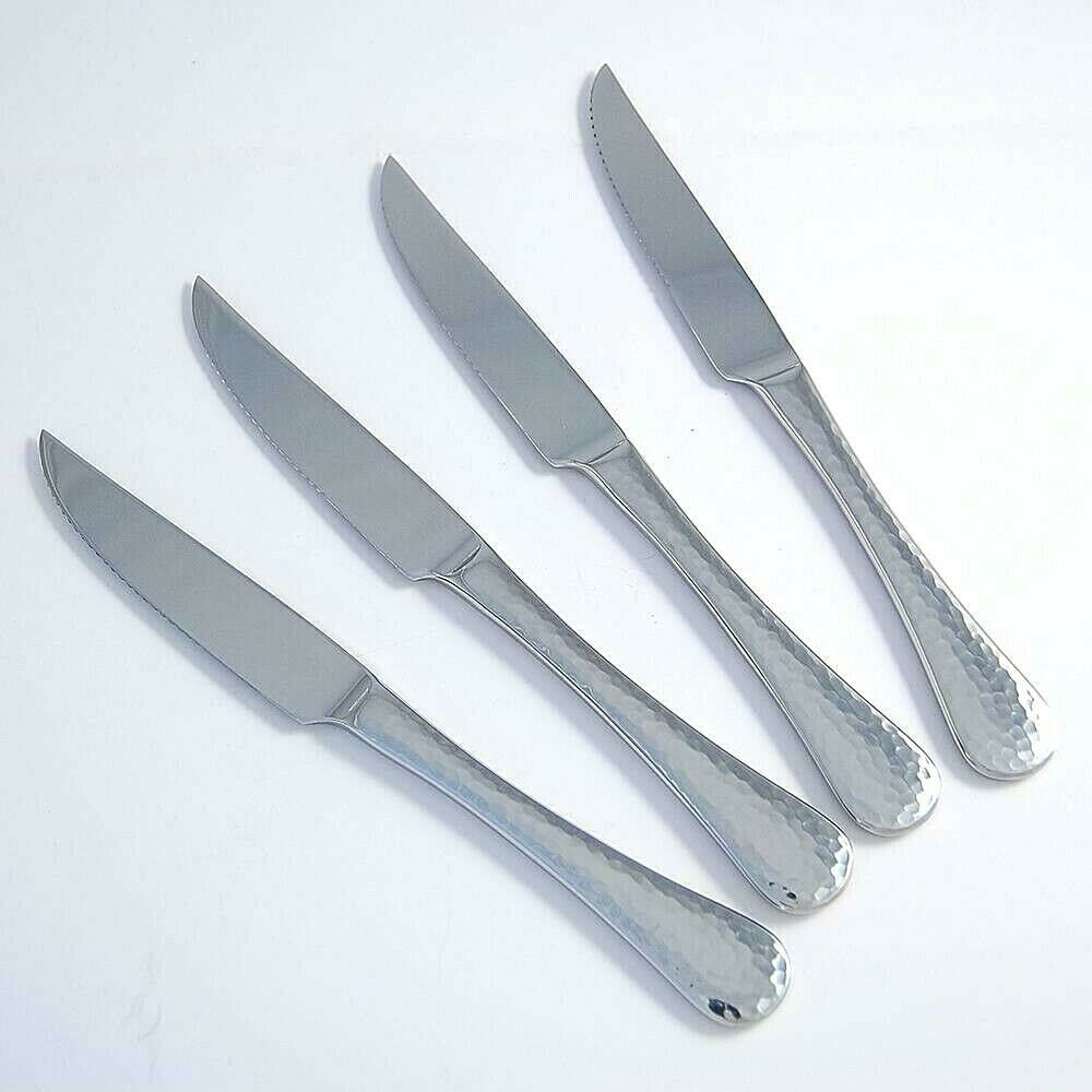 4 steak knives fanned out on a white background.