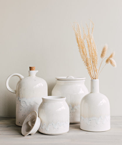 andes cruet arranged with canisters and a vase on a wooden countertop.