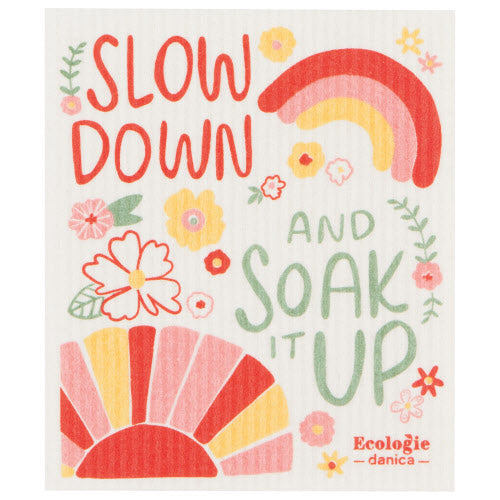 swedish dishcloth with sunshine, rainbow, flowers, and "slow down and soak it up" printed on it.
