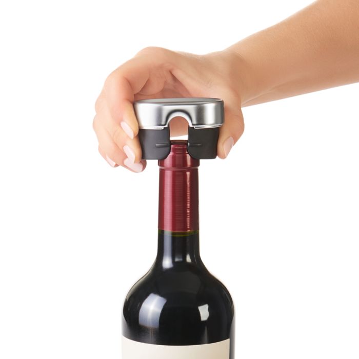 hand using foil cutter on bottle of wine.