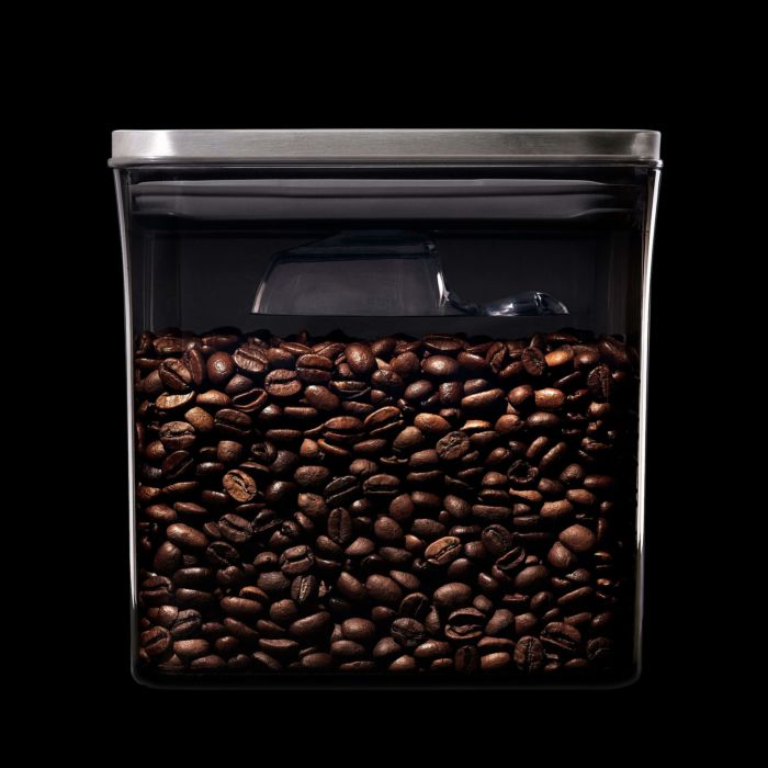 container filled with coffee beans and scoop inside attached to lid.