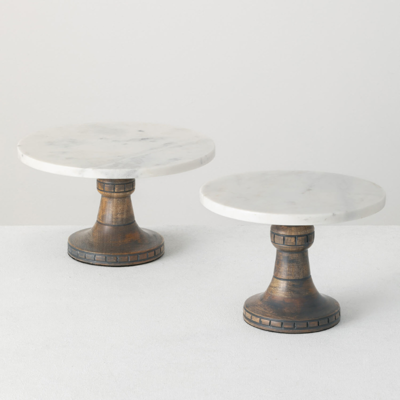 2 marble top sullivans pedestals on white table with white background.