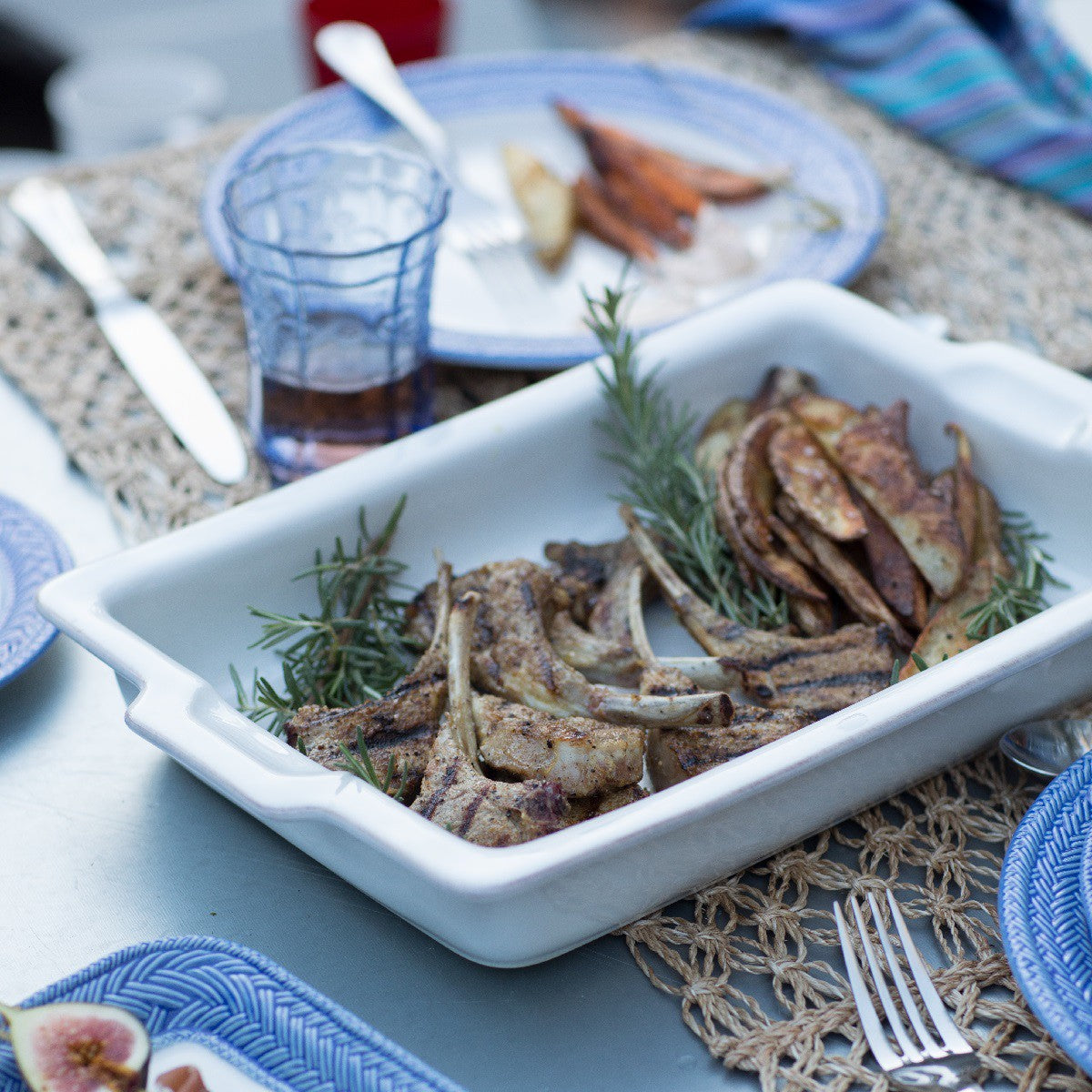 table setting with a puro rectangle baking dish, cup, flatware, and table runner on a gray table.