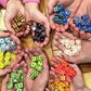 many hands holding dice in a circle above a wooden table.