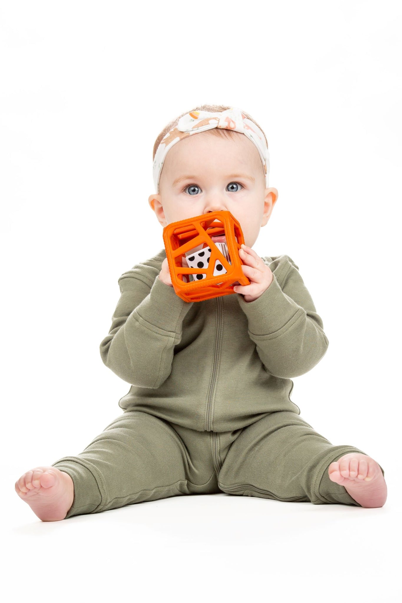 a little girls chewing on the terracotta chew cube against a white background