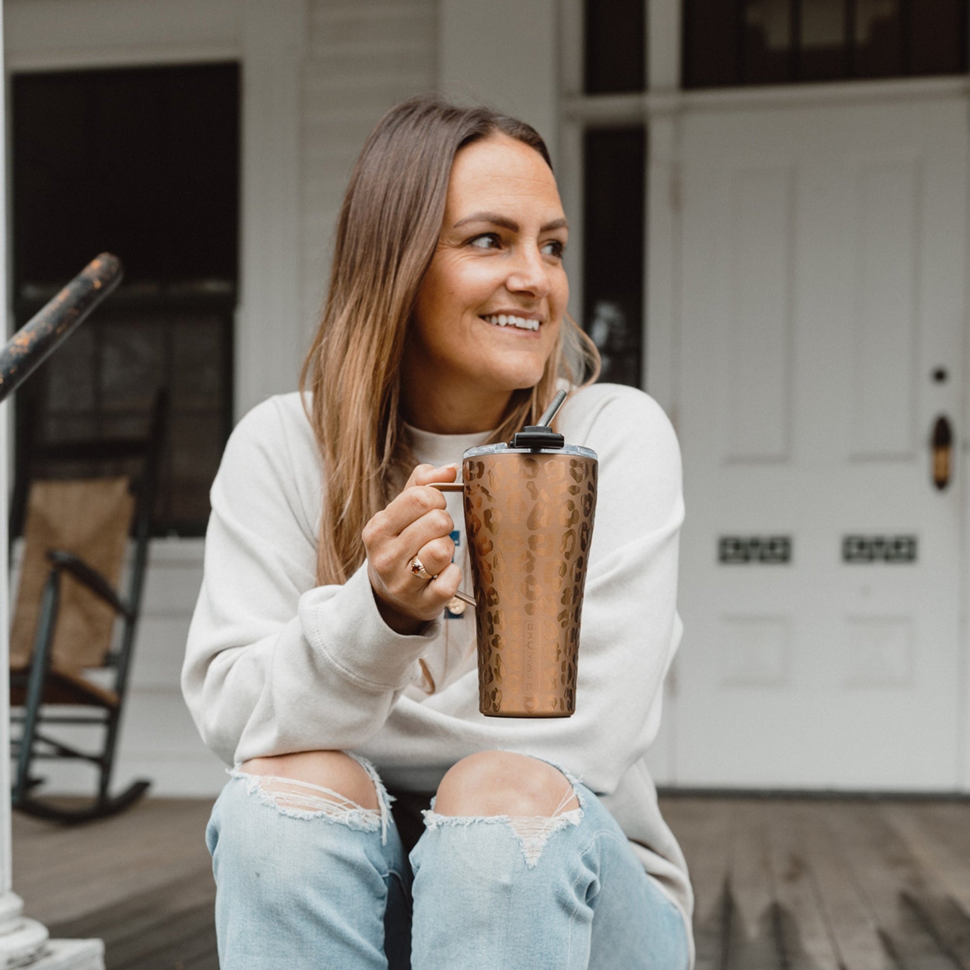 gold leopard 22 ounce toddy being held by a woman sitting on a front porch