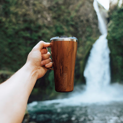 22 ounce toddy being held out with a waterfall behind it