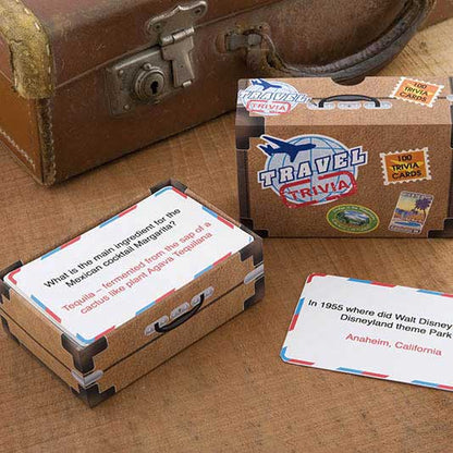 the travel trivia package displayed open  next to an old suitcase on a wood table