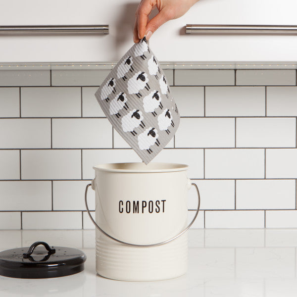 hand holding swedish dish cloth above compost pail.