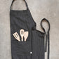 apron folded in half with wooden utensils in pocket.