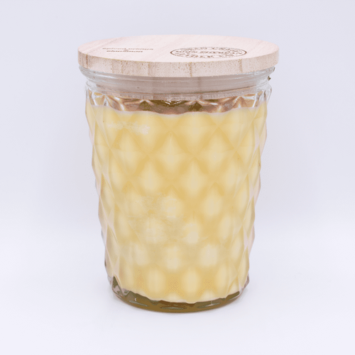 glass jar filled with cream colored wax candle with a wooden lid on a white background.