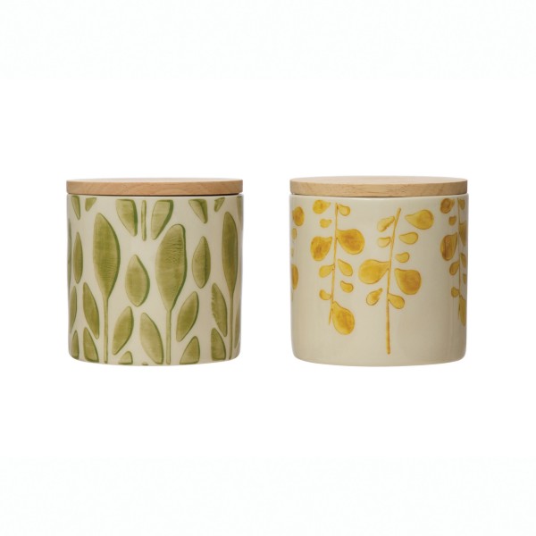 two hand stamped stoneware jars with bamboo lids on a white background